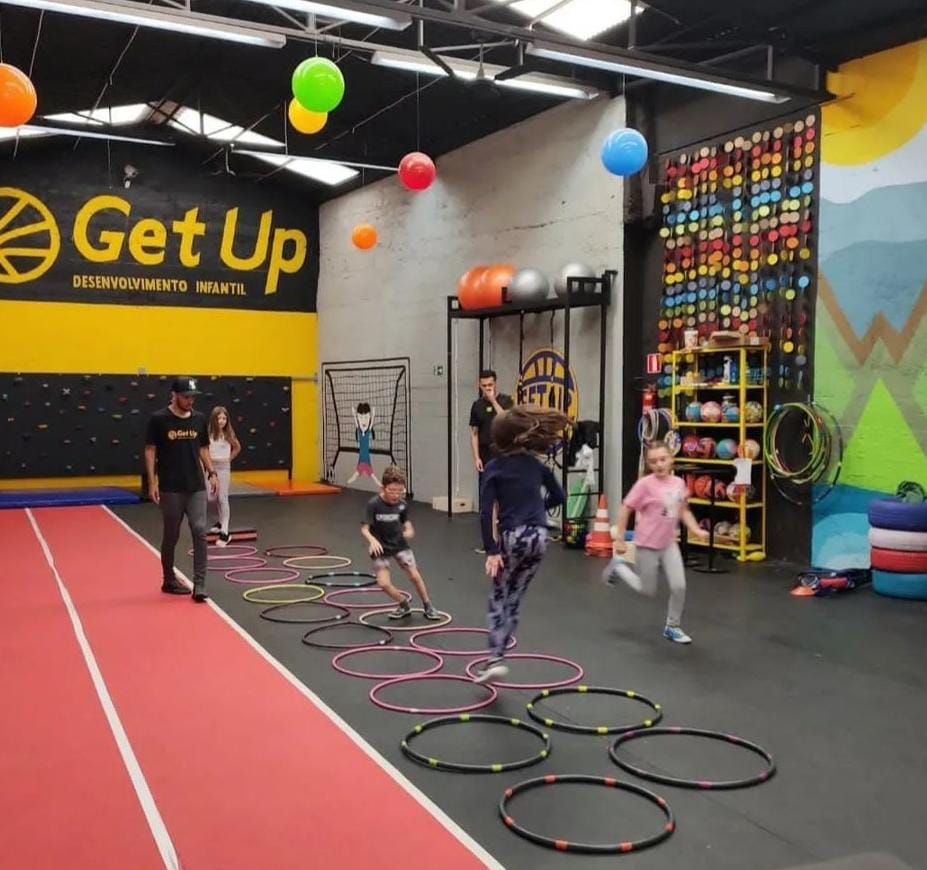 Crianças pulando e correndo com bambolês.