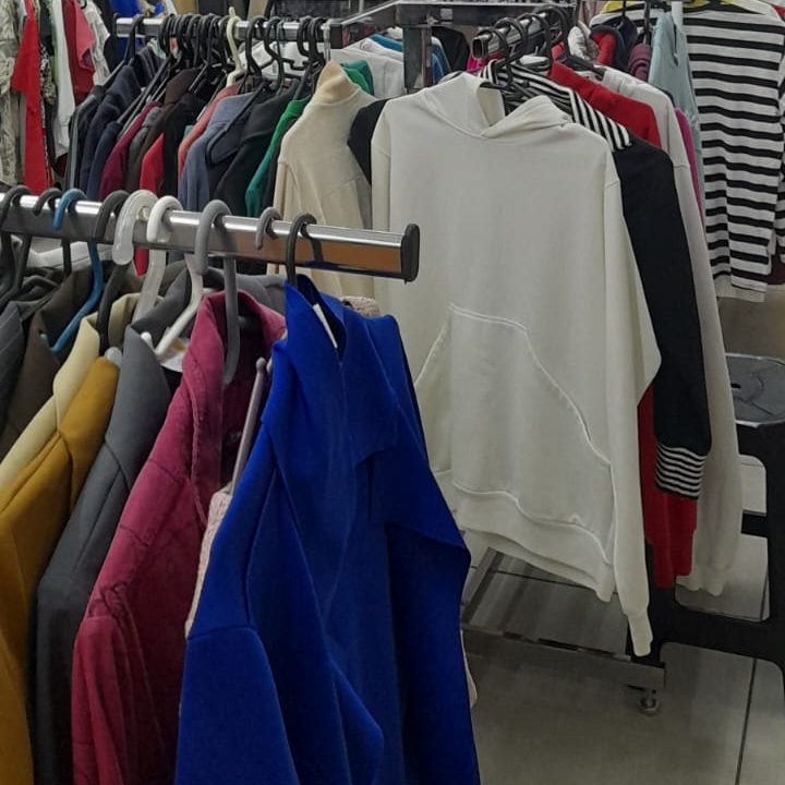 Foto da parte interna de um brechó. Na imagem há araras com roupas penduradas. 